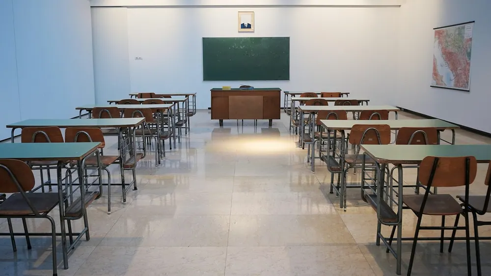 Salon de clases vacio con pupitres y pizarron