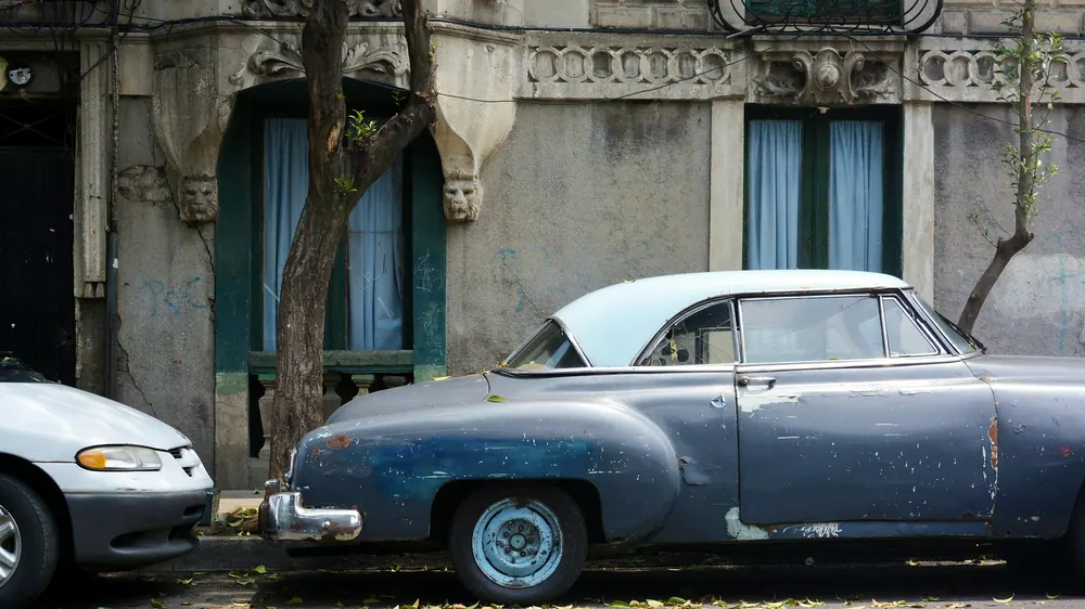 Auto clasico azul estacionado en una calle arbolada