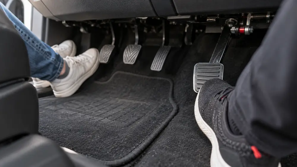 Pedales del alumno y pedal de doble control del instructor en un auto de práctica
